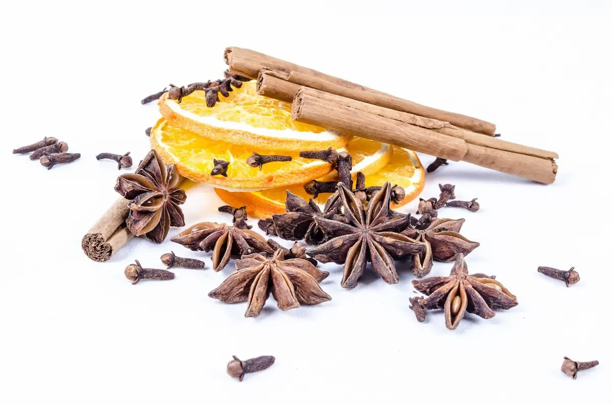 Cloves and orange slices spread on the table, providing a sense of autumn.